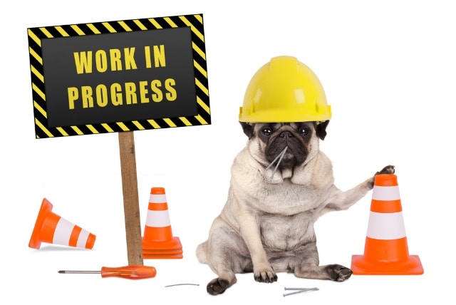 A monkey wearing a hard hat and holding a sign Description automatically generated with medium confidence